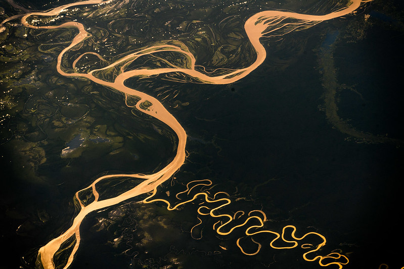 Aufnahme aus dem Weltraum: Der majestätische Amazonas mit seinen Haupt- und Nebenarmen, die sich in zahlreichen Wendungen durch das grüne Dickicht schlängeln. Das Wasser strahlt in einem auffälligen Gelbton.