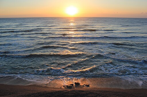 Blick vom Strand aus auf das schwarze Meer. Am Horizont geht die Sonne unter.