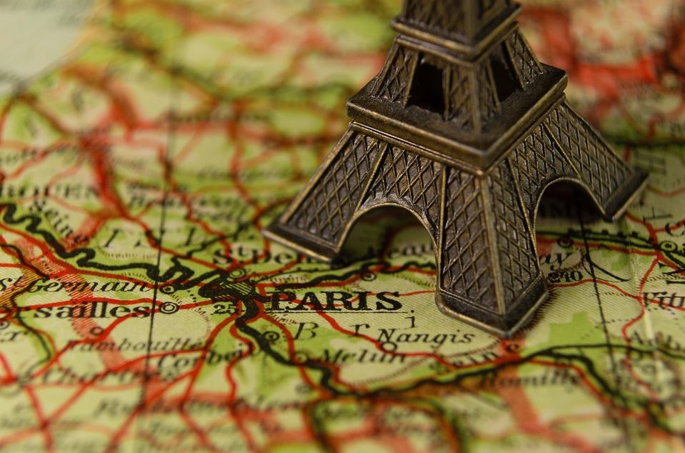 Der untere Teil einer Eiffelturmminiatur steht bei Paris auf einer Landkarte