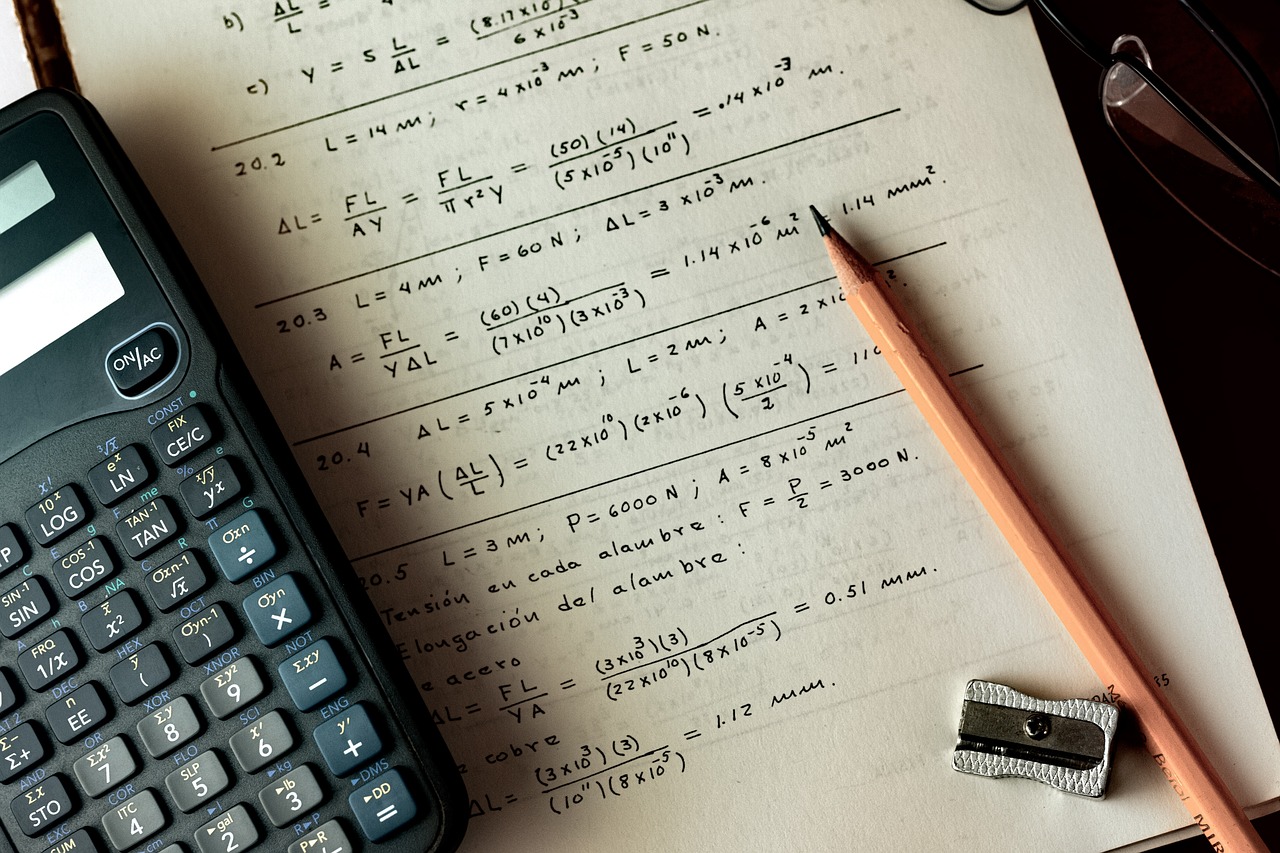 Sammelsurium aus wissenschaftlichem Taschenrechner, Bleistift und Spitzer auf Unterlagen mit mathematischen Berechnungen
