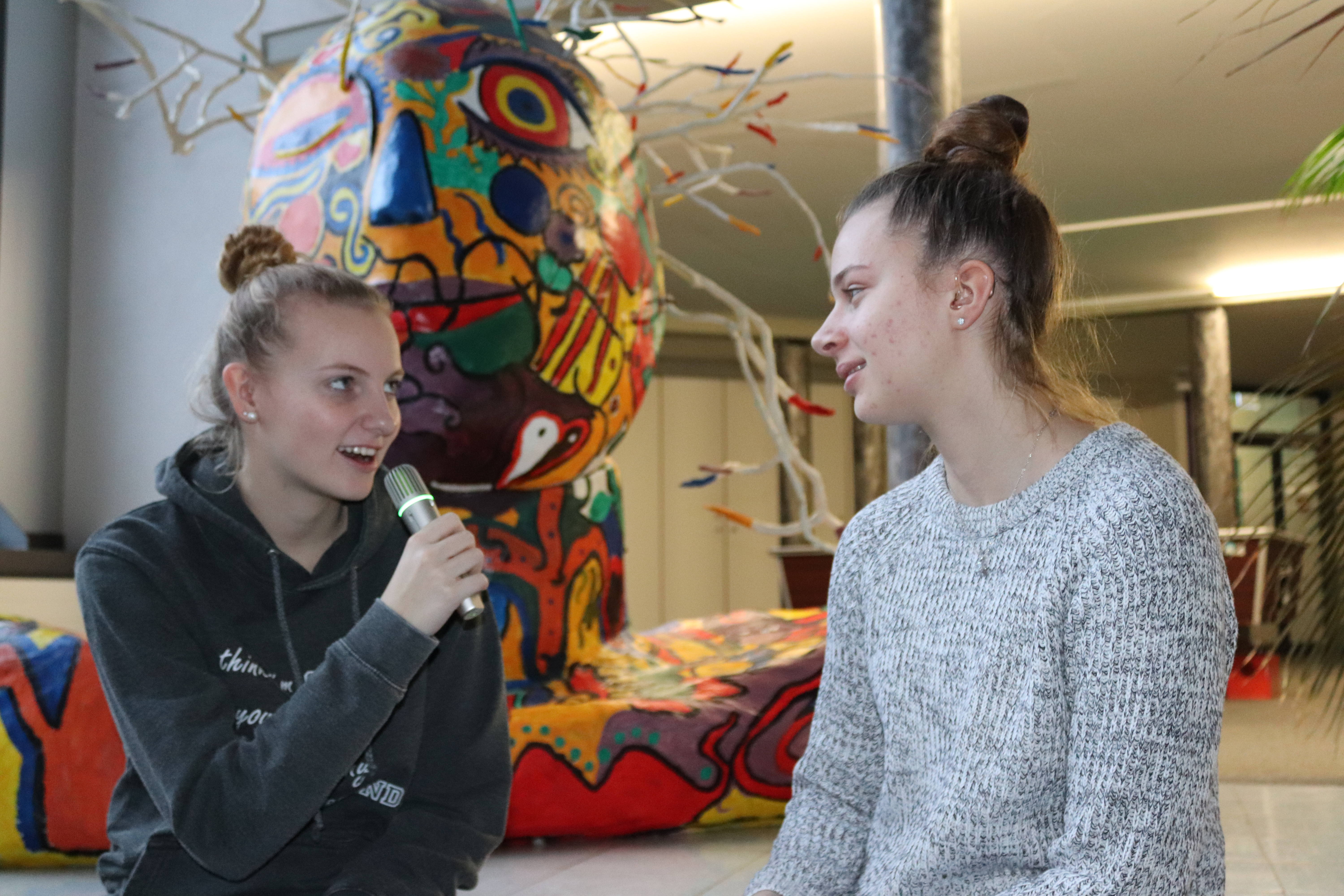 Zwei Schülerinnen im Gespräch – sichtbares Hörgerät, Mikrofon