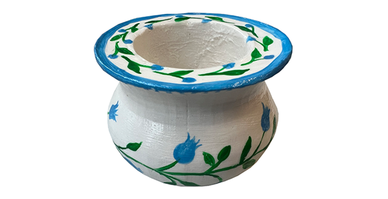 Handbemalter weißer Kerzenhalter aus Ton mit blau-grünem Blumenmuster und blauem Rand.