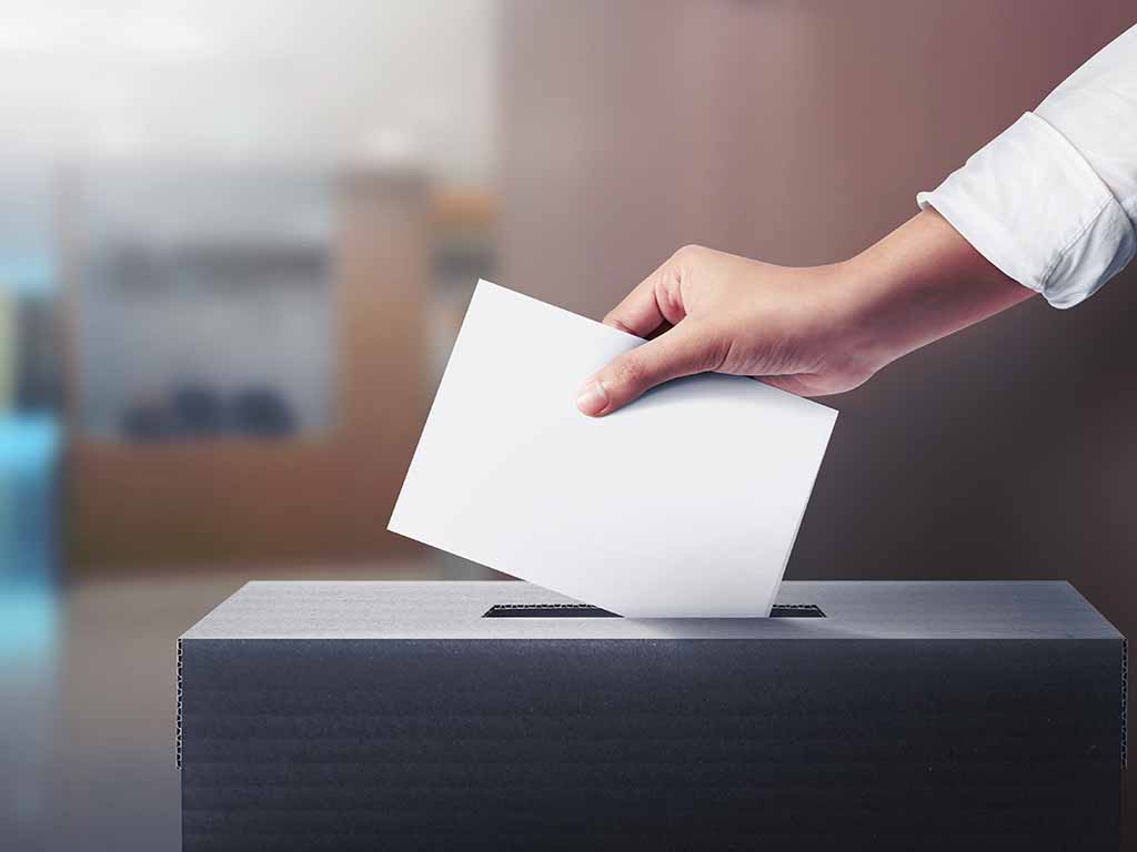 Wahlzettel wird in eine Wahlurne geworfen