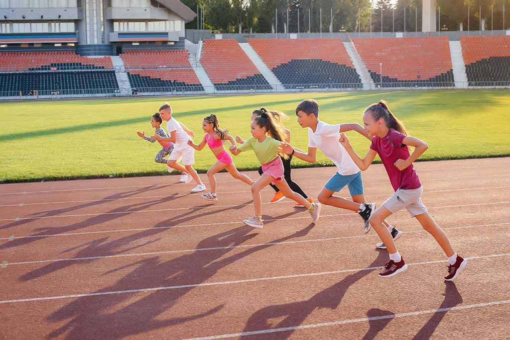 Das Bild zeigt eine Gruppe von Kindern oder Jugendlichen, die auf einer Laufbahn im Stadion starten. Es handelt sich um eine sportliche Aktivität, die den Bereich Leichtathletik, insbesondere einen Sprintwettbewerb, darstellen könnte.
