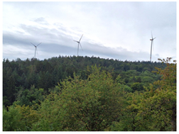 3 Windkrafträder auf einer bewaldeten Anhöhe -ansonsten identisches Bild wie zuvor