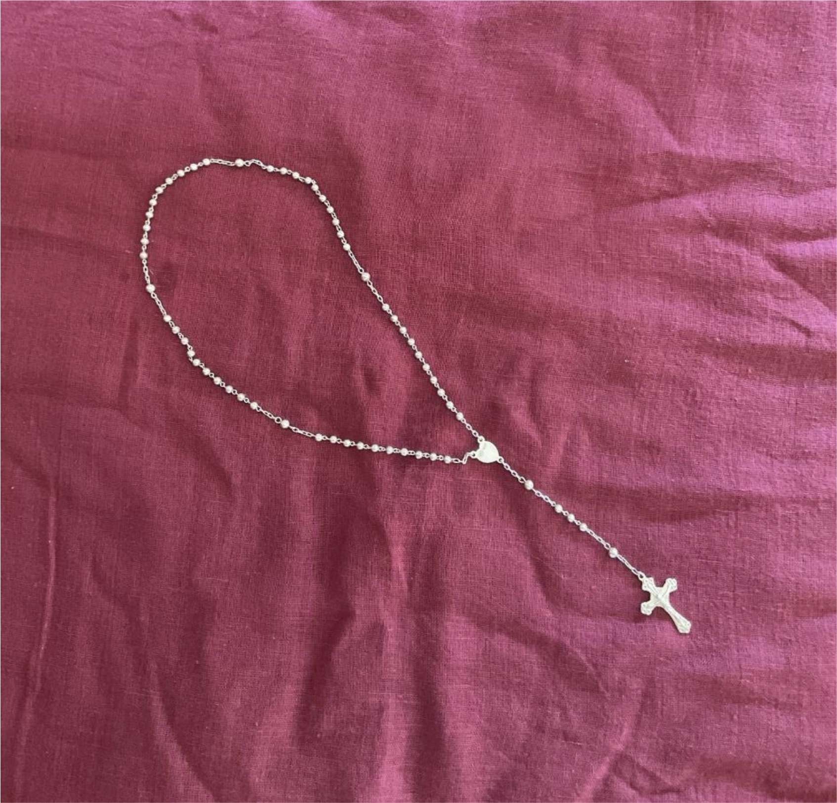 ein Rosenkranz (Halskette) mit einem Kreuz auf rotem Stoff