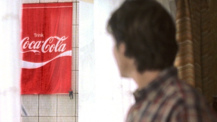 Alex schaut aus dem Fenster auf Coca-Cola-Werbung