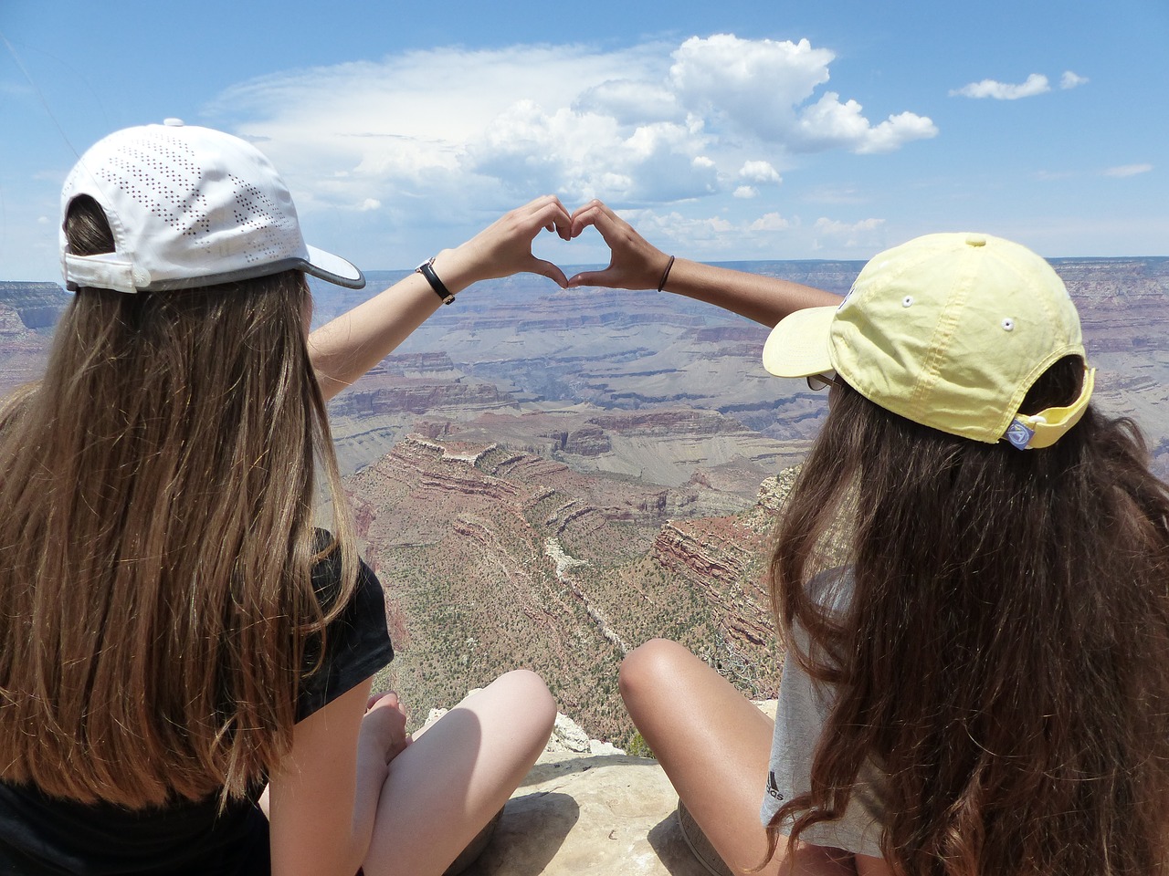 Zwei Teenagerinnen bilden mit den Händen ein Herz